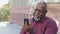 Overjoyed senior black male grandfather waving hand making video call looking at smartphone camera talking on modern