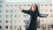 An overjoyed senior woman in glasses dancing in the street on a sunny day