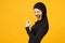 Overjoyed young arabian muslim woman in hijab black clothes doing winner gesture, say Yes isolated on yellow wall