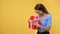 Overjoyed young blonde woman opening festive red package bow celebrating seasonal holiday isolated