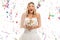 Overjoyed young bride holding bouquet with confetti around her