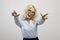 Overjoyed young businesswoman pointing at camera and smiling, aiming both fingers at viewer over light background