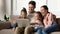 Overjoyed young family laugh using laptop together