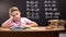 Overloaded schoolboy sitting at desk and failing to solve difficult equation