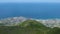 Overlook of coastal city from mountain top facing azure blue calm sea, panorama