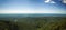 Overlooking view of green mountains with a blue sky in the background