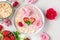 Overnight oats or oatmeal porridge with fresh strawberries, almonds and mint in a bowl with rose flowers