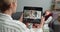 Overshoulder view of woman holding tablet while having video call with male doctor in glasses. Cheerful medical