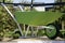 Oversized green, new and empty wheelbarrow use for gardening or construction displayed on a platform. Gardening or