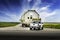 Oversized load of grain silos carried on a semi trailer drives down a rural road