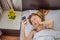 Overslept woman with surprised expression while looking at phone after missed the alarm and woke up late