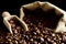 Overturned bag full of coffee beans on black with spatula