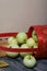 An overturned basket of apples. Nearby are apples and dried maple leaves. Fruit harvest