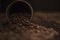 Overturned brown coffee cup and roasted coffee beans on dark kitchen table