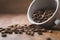 Overturned coffee cup with coffee beans on wood table