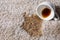 Overturned cup and spilled coffee on beige carpet, closeup