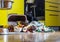 An overturned garbage can and a pile of garbage in the kitchen against the backdrop of a yellow kitchen set