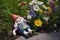 overturned gnome with missing arm near flowers