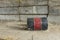 Overturned industrial barrel with debris spilling out next to wall made of concrete blocks