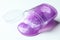 Overturned plastic container with purple slime on background, closeup