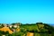 Overview in Acquaviva Picena with hills and green cultivations amongst houses under a blue sky