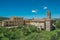 Overview of church and bell tower with trees around in the hamlet of Monteriggioni.