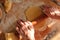 Overview of elderly woman hands rolling out the dough with a rolling pin.