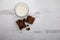 Overview full glass of cold white milk with square pieces of chocolate brownie on wooden background