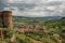 Overview of stone tower, green hills, vineyards and town rooftops near a road. From the city center of Orvieto.