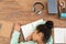 Overview of tired mixed-race schoolgirl keeping her head on open copybook