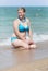 Overweight blonde in bikini sitting in waters edge