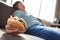 Overweight boy with burger sleeping on sofa