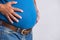 Overweight or fat adult man in very tight jeans on a gray background. Healthcare, medicine concept