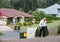 Overweight man having a hard time walking up an extremely steep driveway with neighborhood houses in the background