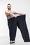 Overweight man holding oversize pants after weight loss on white