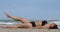 Overweight Mature caucasian woman doing exercise on yoga mat on beach, female is lying and alternately raises his legs