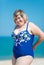 Overweight woman adjusting her blue one-piece swimsuit smiling