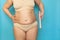 Overweight woman in beige underwear wrap sagging belly with cling film closeup. Body wrapping for weight loss, free copy