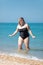 Overweight woman in black one-piece swimsuit at the sea