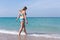 Overweight woman in blue bikini enters the sea water