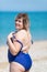 Overweight woman in blue one-piece swimsuit at the sea