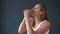 Overweight woman eating hamburger on grey background. The concept of harmful food, excess weight