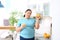 Overweight woman with glass of fresh juice and orange in kitchen.