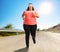 Overweight woman jogging on an open road