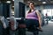 Overweight woman pumps press, exercise in gym