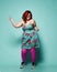 Overweight woman in sunglasses, colorful sundress and tights has fun dancing boogie woogie and laughs on mint
