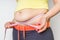 Overweight woman with tape is measuring fat on belly