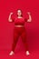 Overweight young beautiful woman training, doing exercises with dumbbells against red studio background. Sport, body