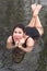 Overweight young woman in black one-piece bathing suit lying in outdoors pool at balneotherapy spa