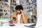 Overwhelmed person at desk with books and laptop in library